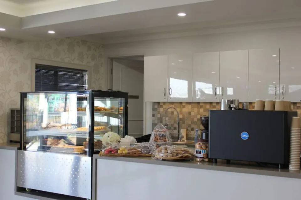 Cafe counter with a glass food display and coffee machine.