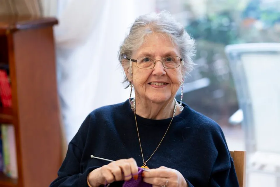 Older woman knitting while seated indoors