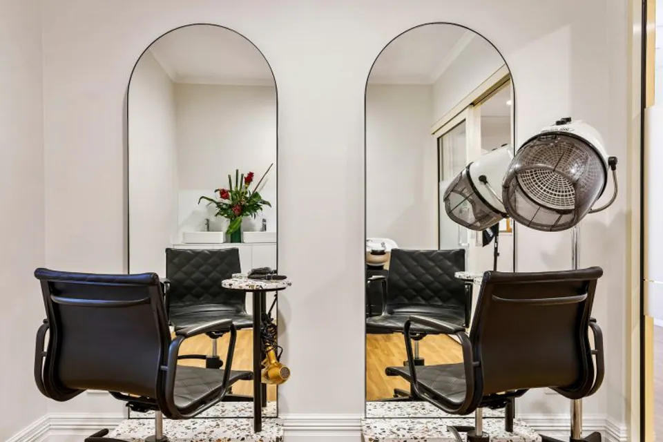 Hair salon with two styling chairs and arched mirrors.