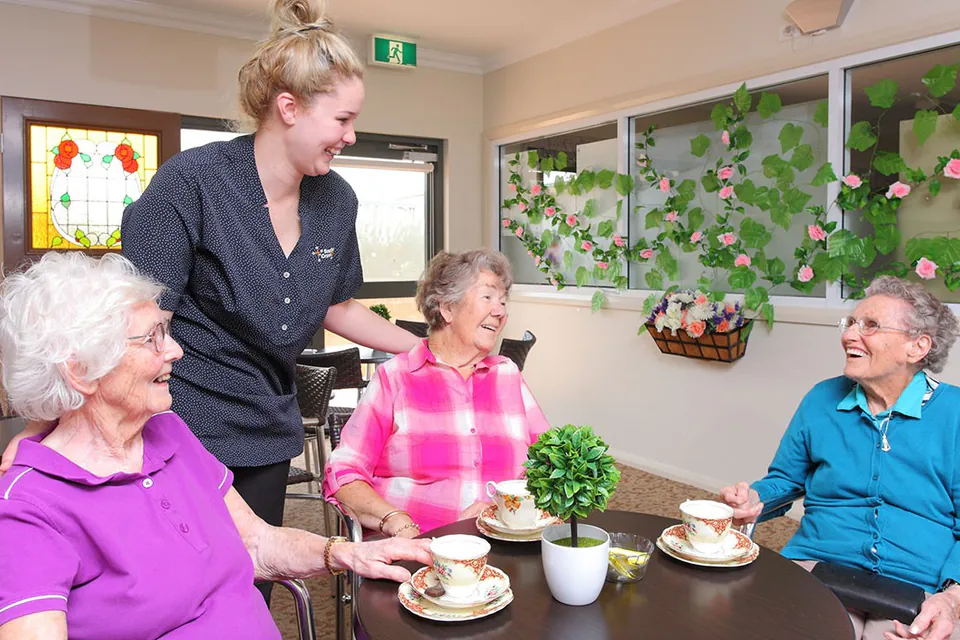 Staff member talking with three residents over tea