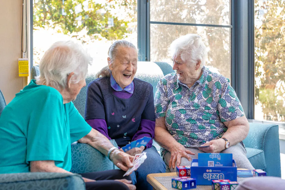 Three residents chatting beside a window