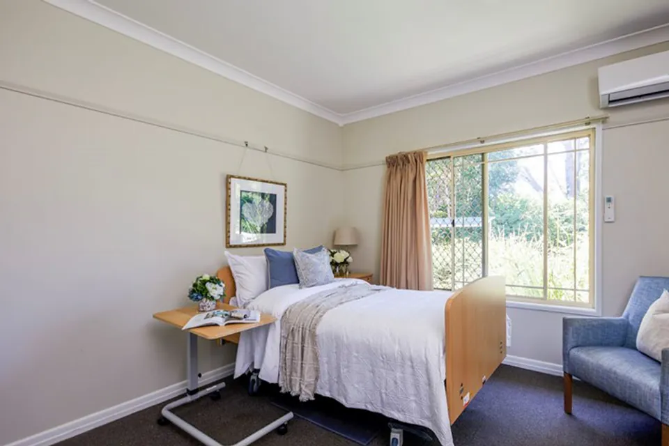 Resident bedroom with care bed and blue armchair