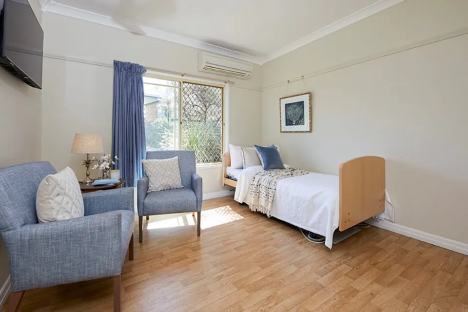 Bedroom with two blue armchairs and a garden window