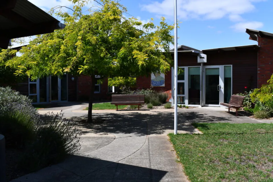 Brick residence wing facing a shaded courtyard and garden.