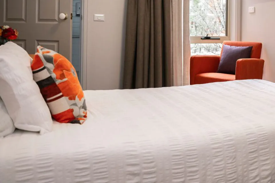 Resident bedroom with a white bed and red armchair.