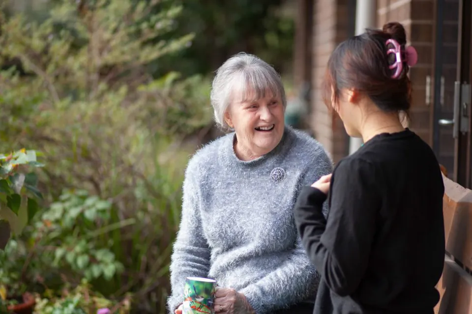 Older woman talking with another person outdoors