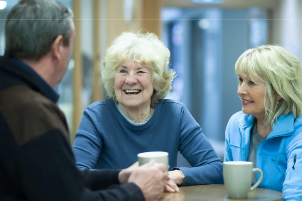 Older woman smiling at a table with visitors