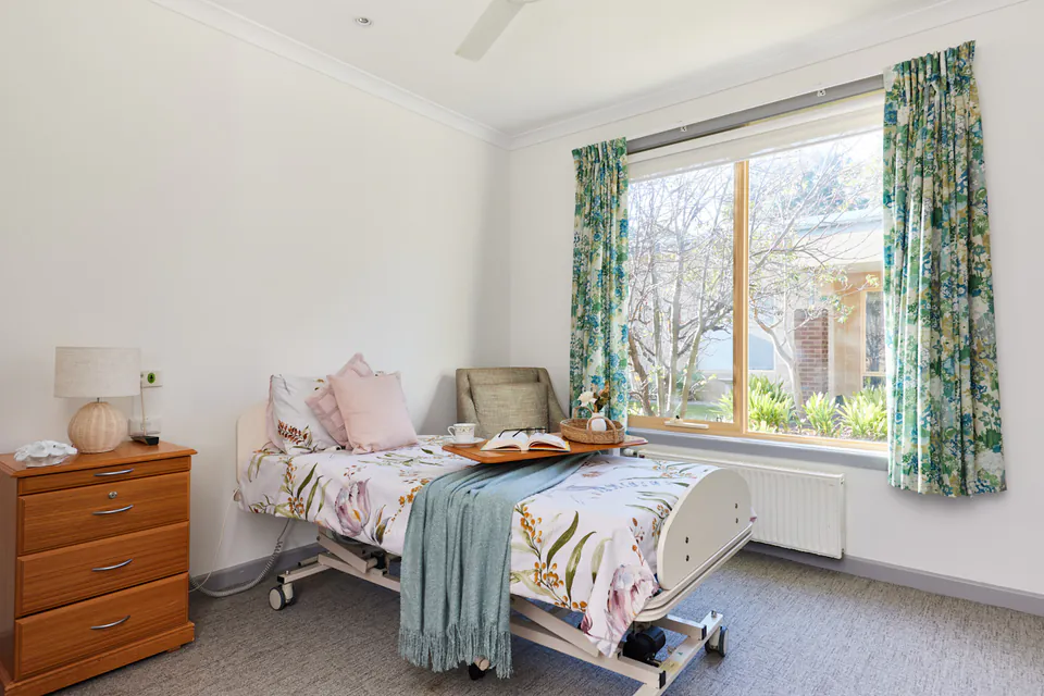 Care bedroom with a floral quilt and garden window