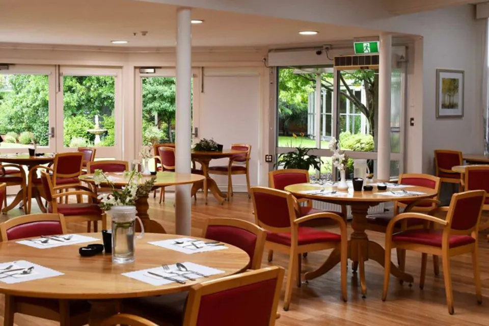 Dining room with round tables set beside garden windows.