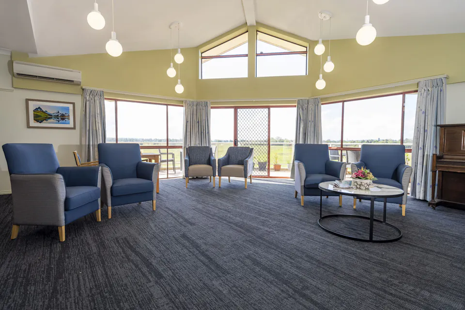 Shared lounge with blue armchairs and wide windows