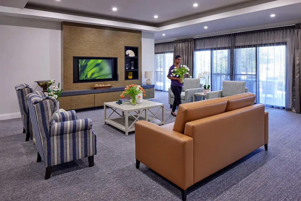 Staff member in a lounge with sofas and television