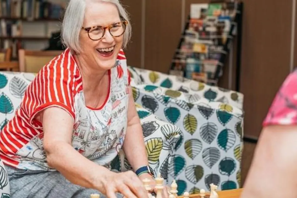 Resident smiling during a table activity in the lounge