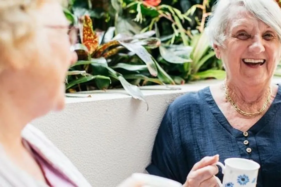 Resident talking with a companion beside garden plants
