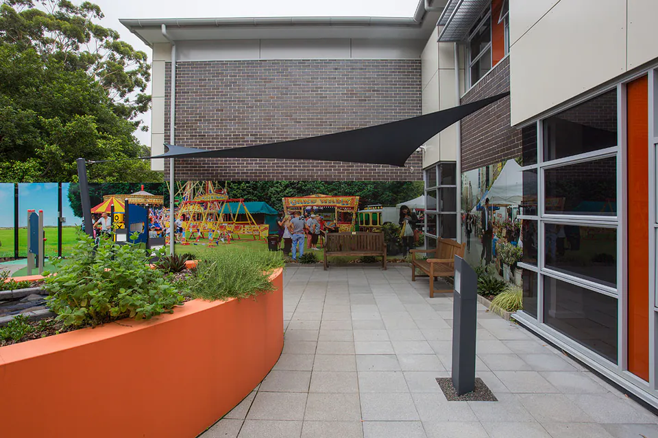 Courtyard with planters, play equipment and people near a building