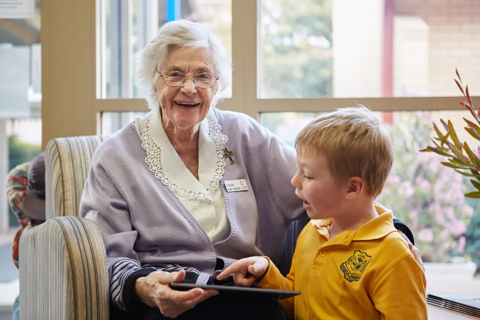 Older woman and young boy seated together by a window