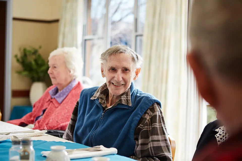 Older man smiling at a dining table