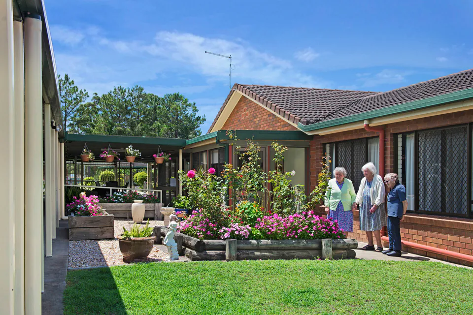 Residents standing beside a flowering courtyard garden