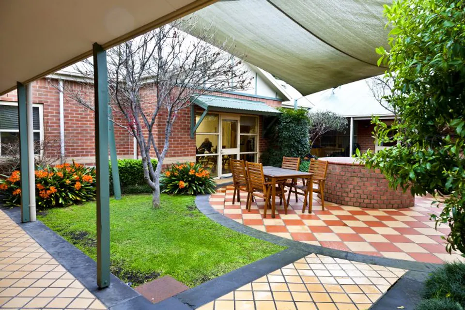 Covered garden patio with a table and chairs.