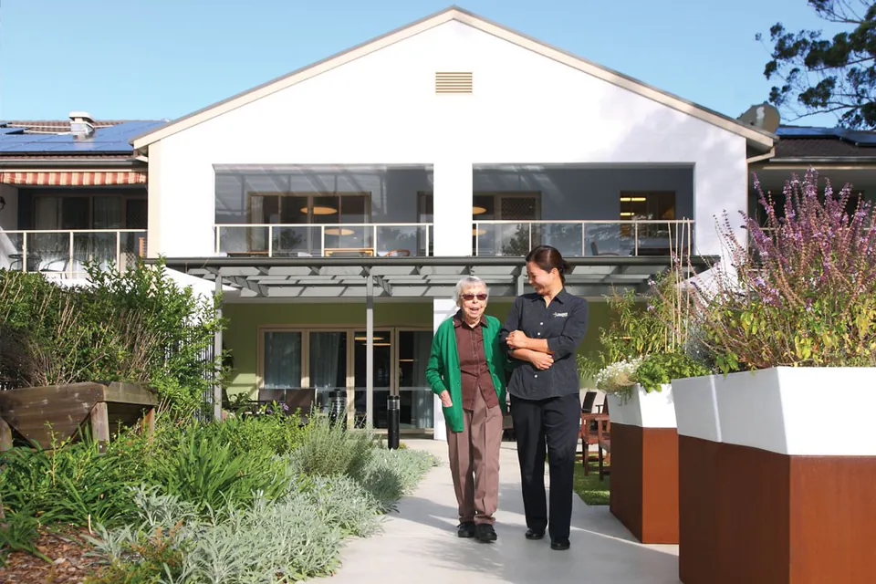 Staff member and resident walking through the front garden
