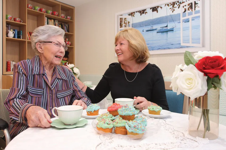 Resident and staff member sharing tea at a table