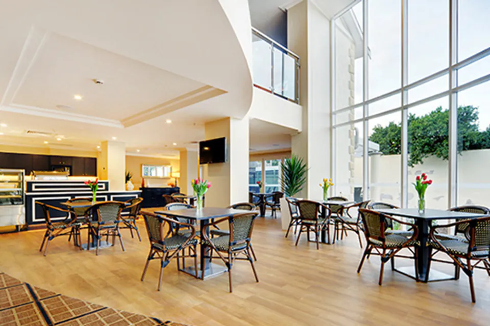 Cafe tables beside tall windows and a piano