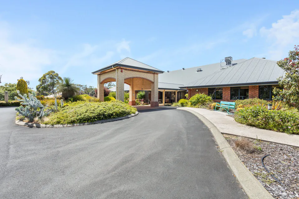 Low brick residence with covered entrance and landscaped drive