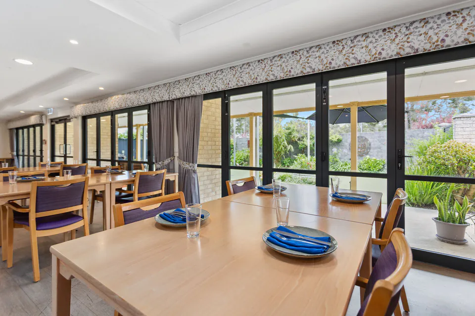 Dining tables set beside a long wall of windows
