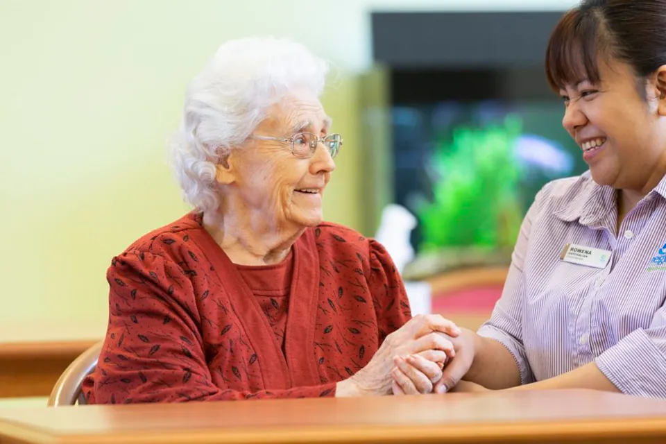 Resident and staff member smiling together at a table