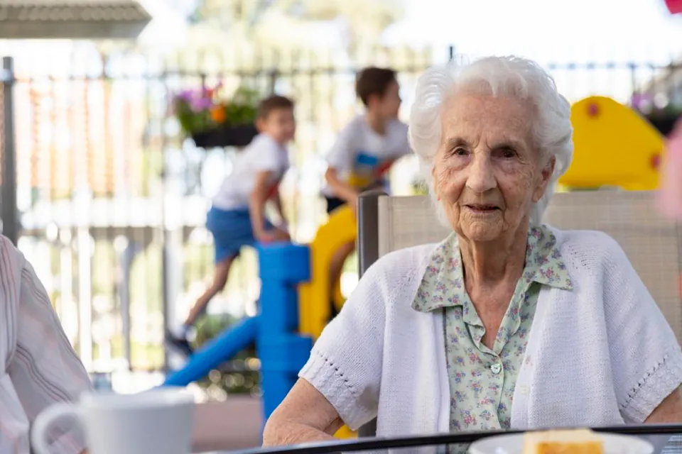 Resident seated outdoors with visitors in the background