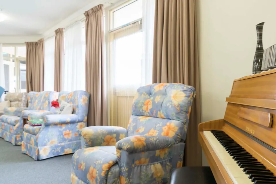Lounge chairs and piano beside tall windows