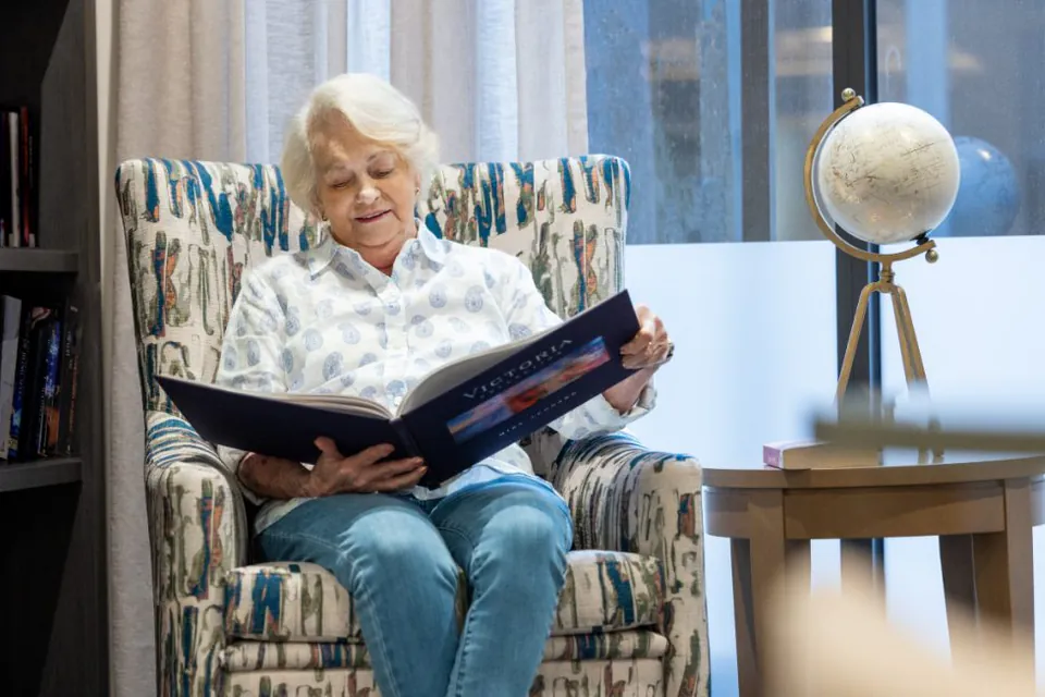 Resident reading in an armchair by a bookshelf