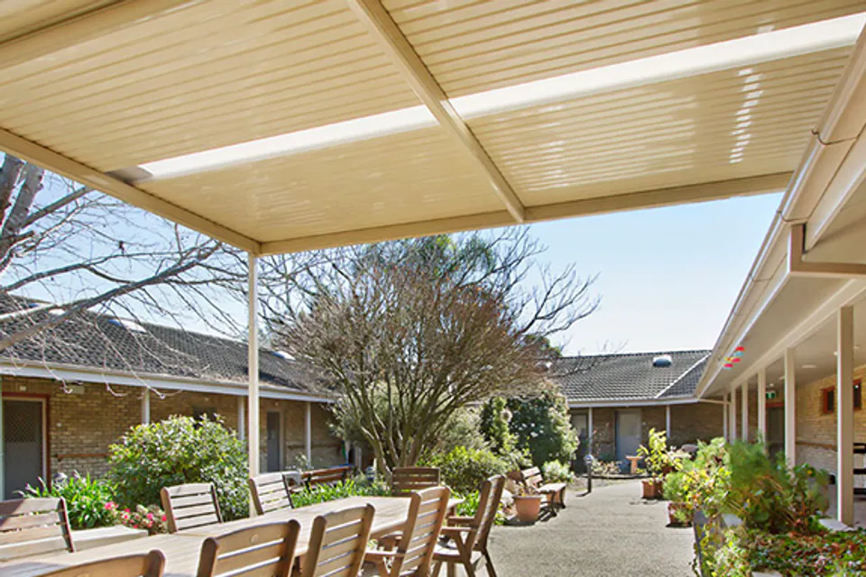 Covered outdoor dining table in a planted courtyard