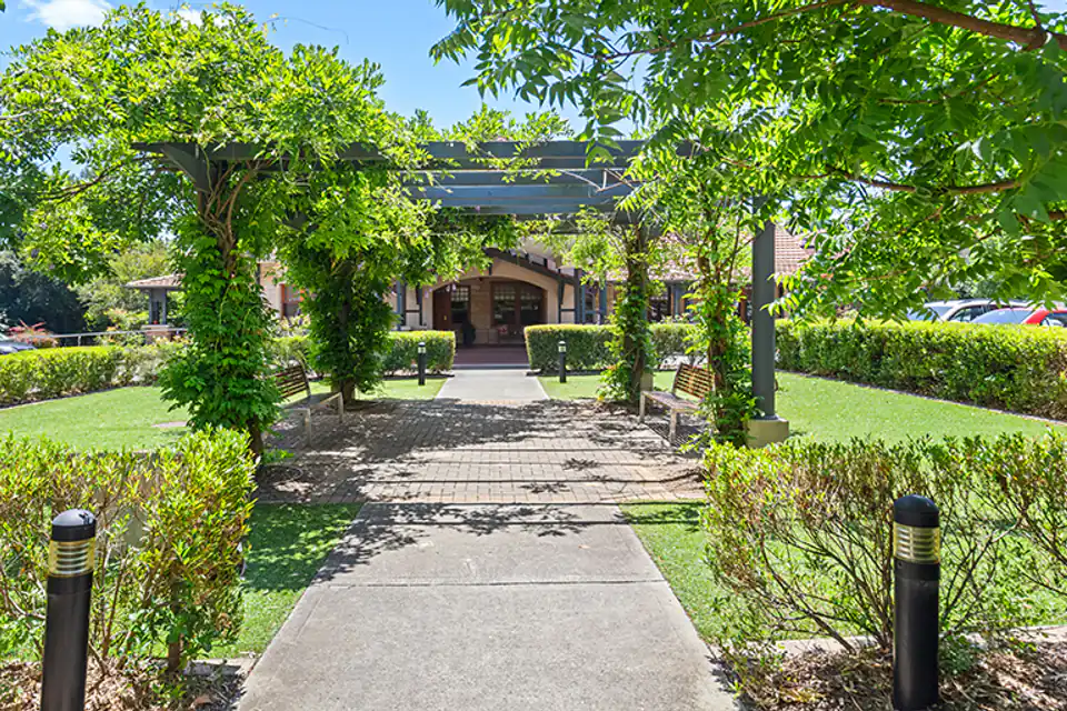 Garden path leading through trees to a brick building
