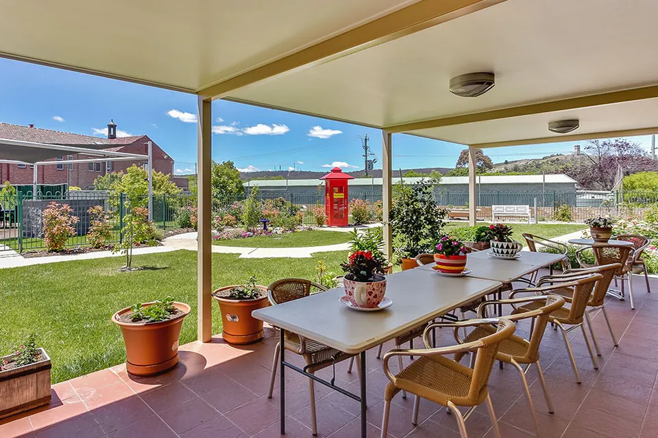 Covered terrace with dining table overlooking the lawn