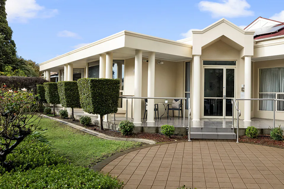 Entrance path leading to a low-rise building with garden beds