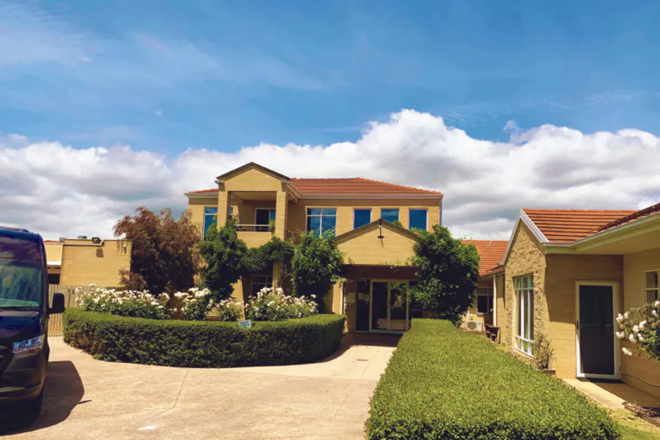 Residence entrance beyond landscaped shrubs.