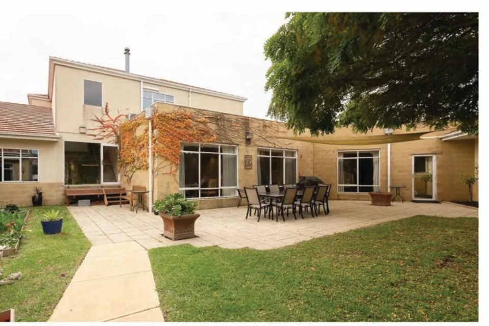 Residence courtyard with outdoor dining table and lawn.