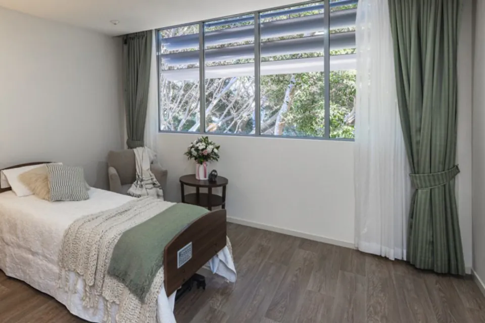 Bedroom with a single bed, bedside table and garden-facing window