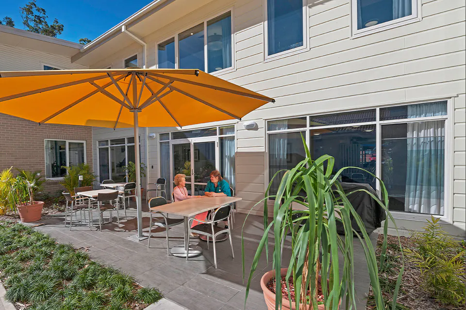 Residents seated beneath a yellow umbrella on the patio