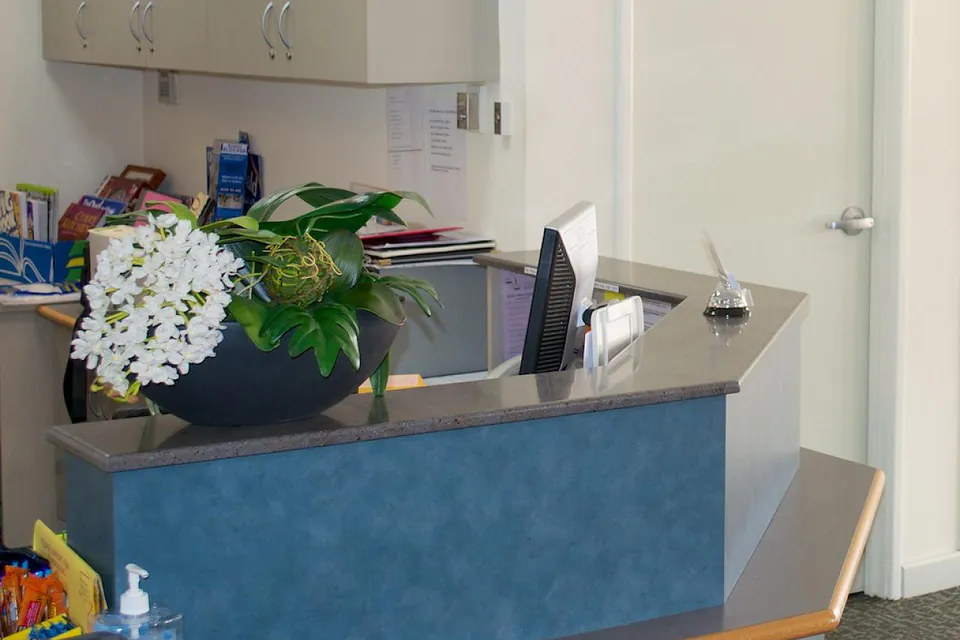 Reception desk with flowers beneath white cabinetry.
