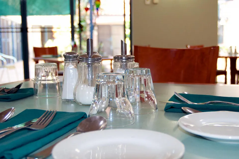 Dining table set with plates, glasses and teal napkins.