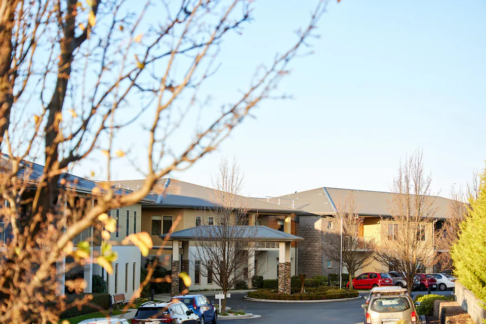 Building exterior behind trees and a planted garden