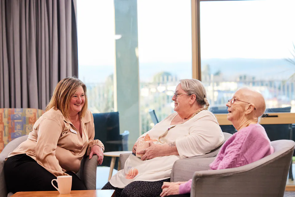 Woman talking with two older residents beside a window