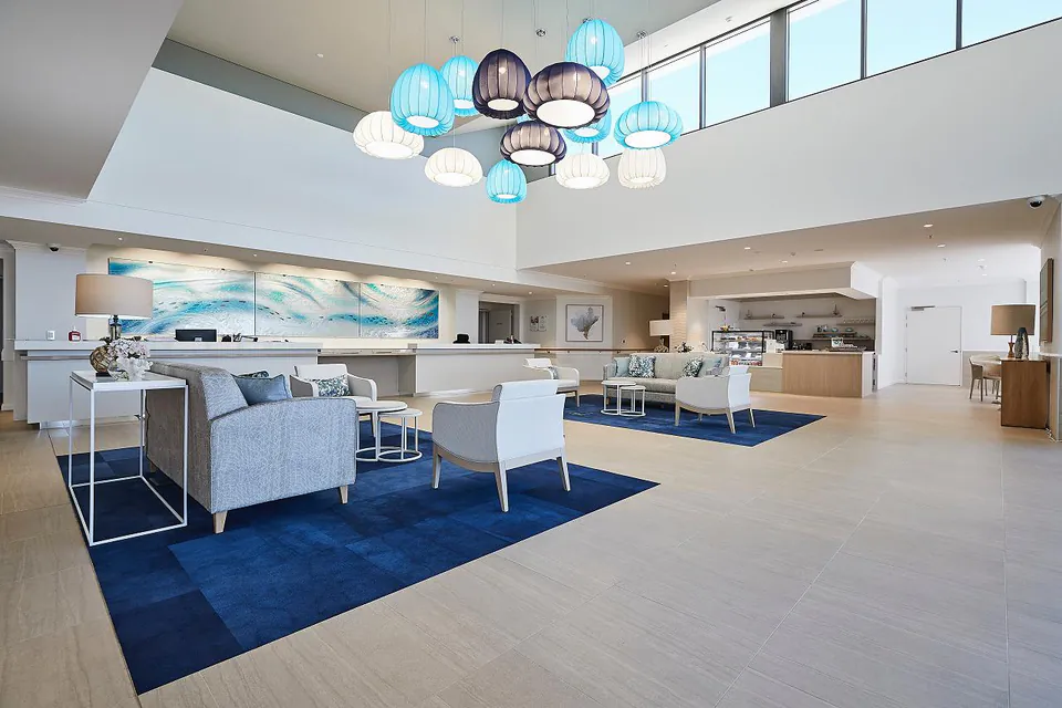 Large lounge with blue rugs, sofas and colourful pendant lights.