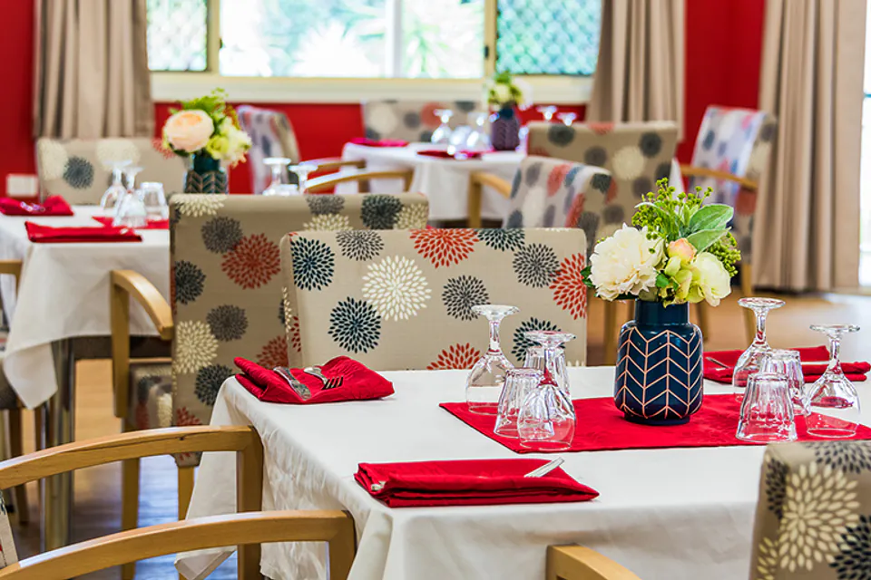 Dining table set with red napkins and patterned chairs
