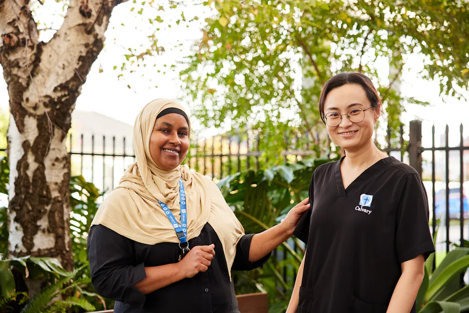 Two care workers standing together in a garden