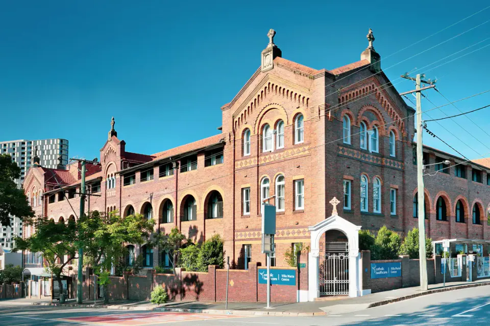 Three-storey red brick building with arched windows on a street corner