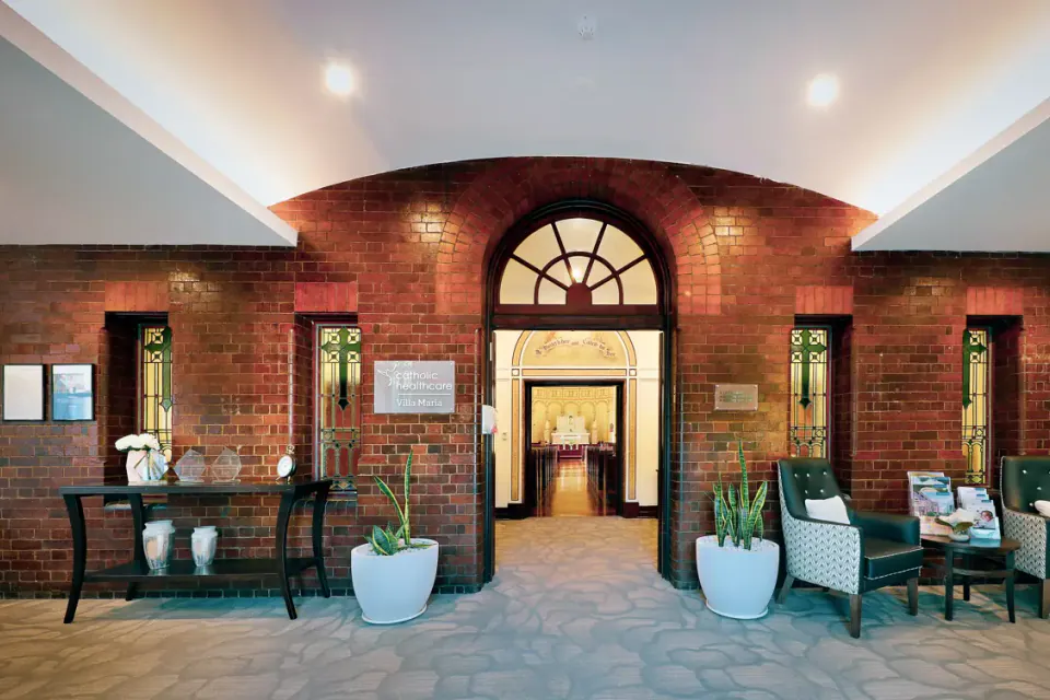 Entrance foyer with a brick archway, armchairs and a console table, looking through to a chapel