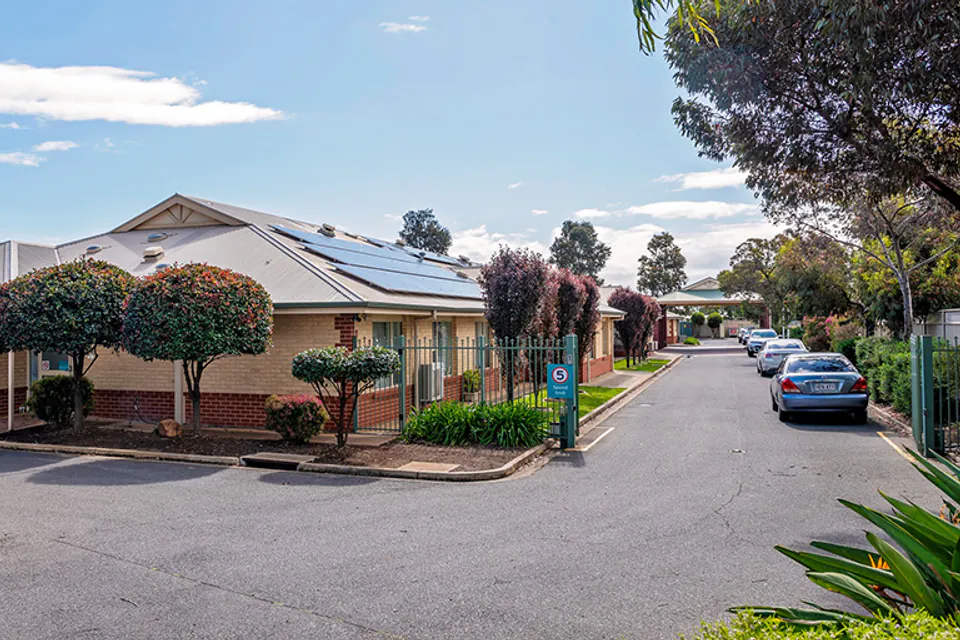 Single-storey brick building beside a driveway and trees