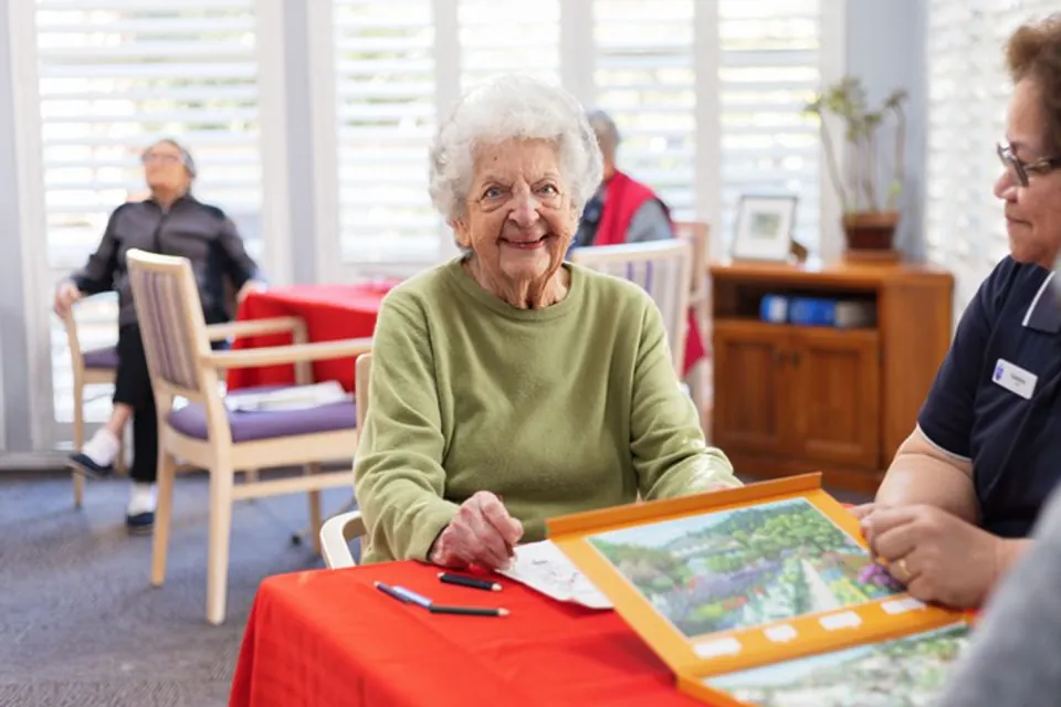 Resident and staff member working on a picture puzzle